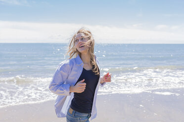 Porträt einer lächelnden jungen Frau beim Laufen am Meer - BOYF000291