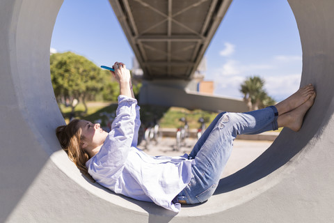 Italien, eine Frau macht ein Selfie mit ihrem Smartphone, während sie sich im Schatten ausruht, lizenzfreies Stockfoto