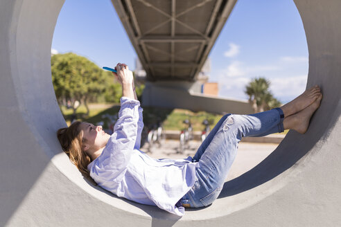 Italien, eine Frau macht ein Selfie mit ihrem Smartphone, während sie sich im Schatten ausruht - BOYF000303