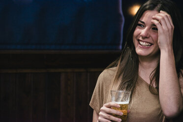 Lachende Frau mit einem Glas Bier in einer Bar - ABZF000387