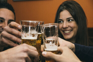 Friends toasting with glasses of beer in a bar - ABZF000391