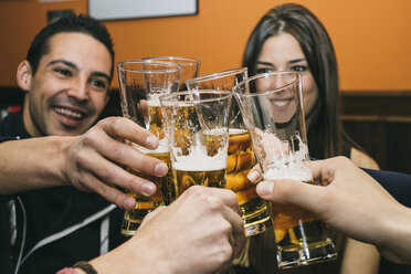 Friends toasting with glasses of beer in a bar - ABZF000392