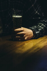 Hand eines Mannes mit einem Glas Bier in einer Bar - ABZF000396