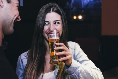 Lächelnde Frau trinkt ein Glas Bier mit einem Mann in einer Bar - ABZF000397