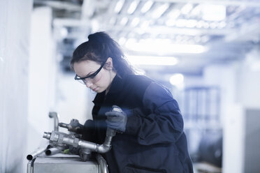 Junge Frau arbeitet an einer Maschine in einer Fabrik - SGF002049