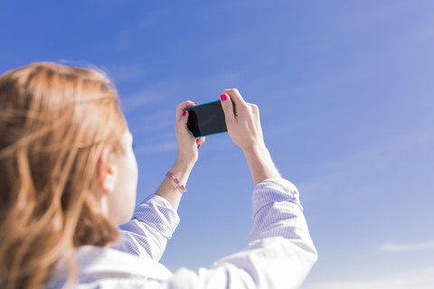 Italien, Lignano Sabbiadoro, Frau mit Smartphone, Selfie, lizenzfreies Stockfoto