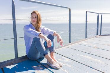 Italy, Lignano Sabbiadoro, woman sitting with smartphone on jetty - BOYF000311