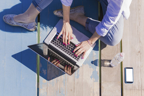 Frau benutzt Laptop auf der Holzpromenade - BOYF000319