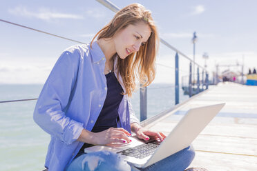 Woman using laptop on jetty - BOYF000320