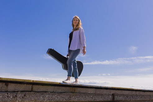 Junge Frau mit Gitarrenkoffer auf dem Bootssteg - BOYF000327
