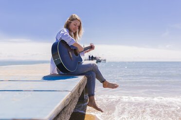 Young woman with guitar sitting on jetty - BOYF000333
