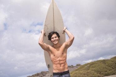 Porträt eines lächelnden jungen Mannes mit Surfbrett - SIPF000409