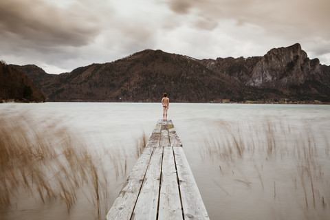 Austria, Lake Mondsee, Rear view of nude man standing on pier stock photo
