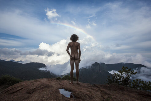 Sri Lanka, Horton Plains National Park, Rear view of nude man standing on viewing point, rainbow - WV000761