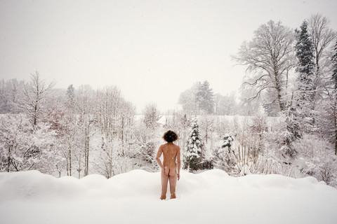 Rückansicht eines nackten Mannes, der im Schnee steht, lizenzfreies Stockfoto