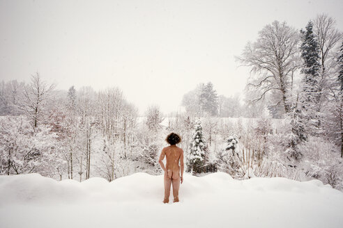 Rear view of nude man standing in snow - WV000766