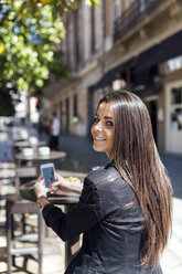 Junge schöne Frau mit Smartphone, Straßencafé - MGOF001800