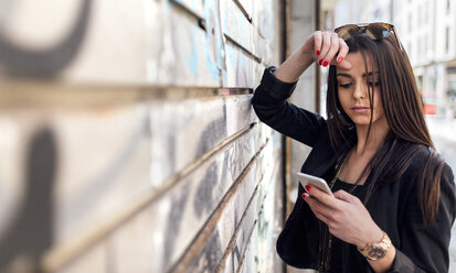 Junge schöne Frau sendet eine Nachricht mit dem Smartphone - MGOF001807