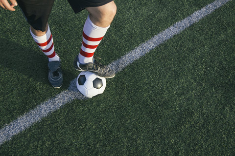 Beine eines Fußballspielers mit Ball auf dem Fußballplatz, lizenzfreies Stockfoto