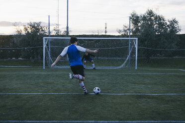 Football player kicking a ball in front of a goal with a goalkeeper - ABZF000474