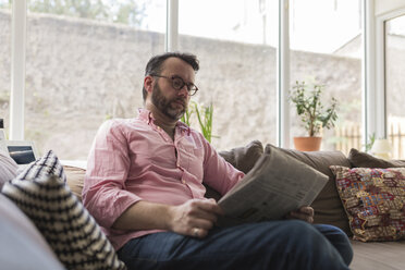 Älterer Mann sitzt auf der Couch und liest Zeitung - BOYF000357