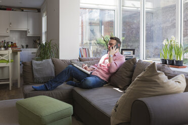 Älterer Mann sitzt auf der Couch und telefoniert - BOYF000360