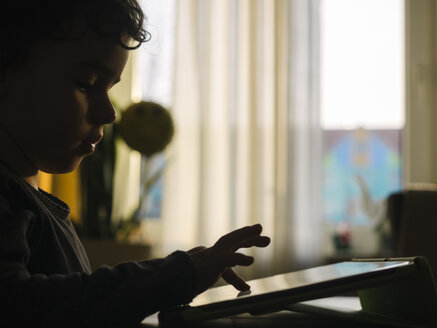Silhouette eines kleinen Mädchens, das mit einem digitalen Tablet zu Hause spielt - KRPF001738