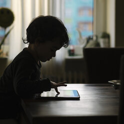 Silhouette of little girl playing with digital tablet at home - KRPF001739