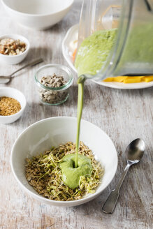 Smoothie-Bowl mit Leinsamen, Sonnenblumenkernen und Nüssen, Gießen von Smoothie - EVGF002929