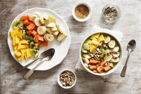 Smoothie bowl with different fruits, mango, papaya, kiwi, banana and pear and toppings, lineseeds, sunflower-seeds and nuts - EVGF002931