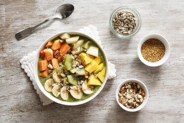 Smoothie bowl with different fruits, mango, papaya, kiwi, banana and pear and toppings, lineseeds, sunflower-seeds and nuts - EVGF002932