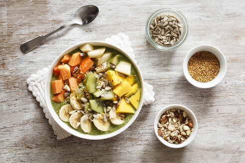 Smoothie Bowl mit verschiedenen Früchten, Mango, Papaya, Kiwi, Banane und Birne und Toppings, Leinsamen, Sonnenblumenkernen und Nüssen - EVGF002932