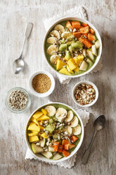 Smoothie Bowl mit verschiedenen Früchten, Mango, Papaya, Kiwi, Banane und Birne und Toppings, Leinsamen, Sonnenblumenkernen und Nüssen - EVGF002934