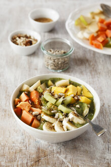 Smoothie Bowl mit verschiedenen Früchten, Mango, Papaya, Kiwi, Banane und Birne und Toppings, Leinsamen, Sonnenblumenkernen und Nüssen - EVGF002935