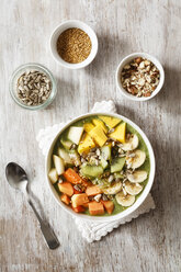 Smoothie bowl with different fruits, mango, papaya, kiwi, banana and pear and toppings, lineseeds, sunflower-seeds and nuts - EVGF002936