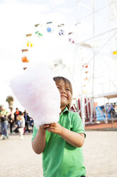 Glücklicher kleiner Junge mit Zuckerwatte auf dem Jahrmarkt - VABF000479