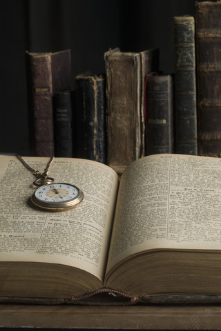 Aufgeschlagenes Buch mit alter Taschenuhr, lizenzfreies Stockfoto