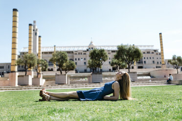 Spain, Barcelona, woman relaxing on lawn in the city - JRFF000598