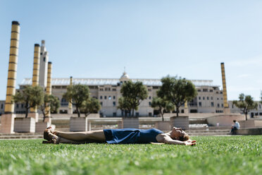 Spain, Barcelona, woman relaxing on lawn in the city - JRFF000599
