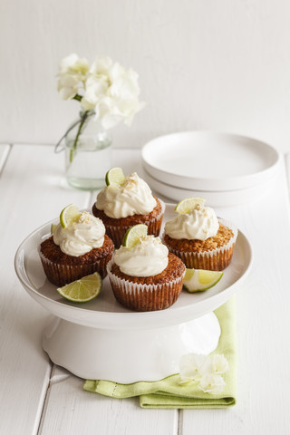 Vier Limetten-Cupcakes mit Frischkäsebelag auf Tortenständer, lizenzfreies Stockfoto