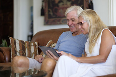 Älteres Paar teilt sich digitales Tablet auf der Couch - ABAF002006
