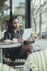 Porträt einer jungen Frau, die in einem Café sitzt und ein digitales Tablet benutzt - ZEDF000092