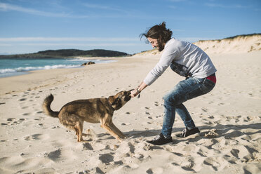 Mann spielt mit seinem Mischling am Strand - RAEF001152