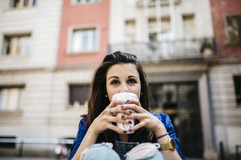 Spain, Barcelona, young woman with a coffee in the city - JRFF000613