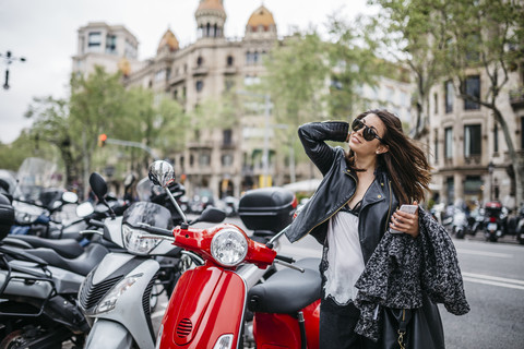 Spanien, Barcelona, junge Frau in der Stadt neben geparkten Motorrollern, lizenzfreies Stockfoto