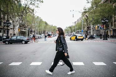 Spanien, Barcelona, junge Frau in der Stadt beim Überqueren der Straße - JRFF000624