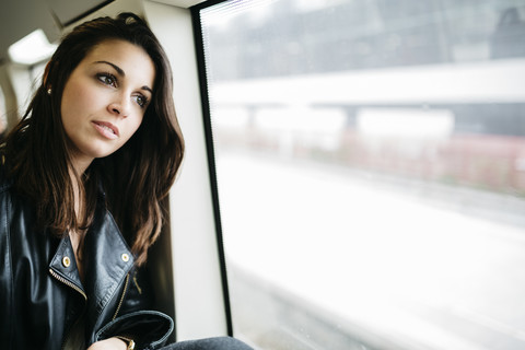 Junge Frau im Zug schaut aus dem Fenster, lizenzfreies Stockfoto