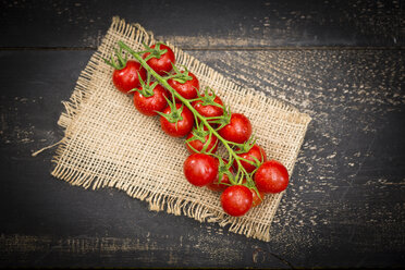 Bunch tomatoes on jute and dark wood - MAEF011470