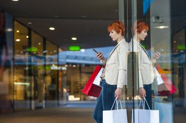 Young woman with cell phone and shopping bags - DIGF000401