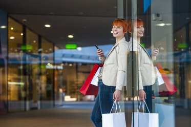 Happy young woman with cell phone and shopping bags - DIGF000402
